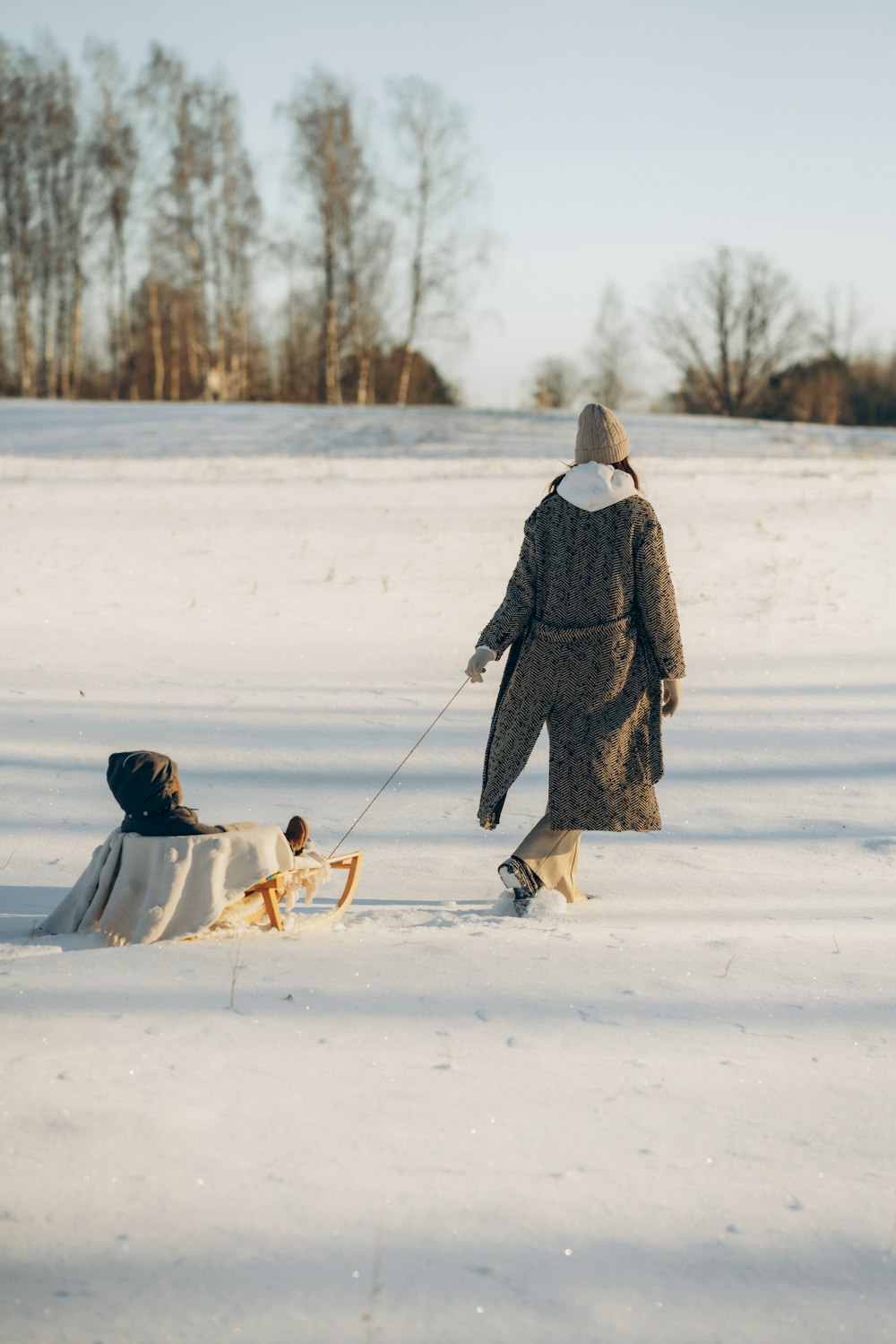 a woman pulling a child on a sled in the snow