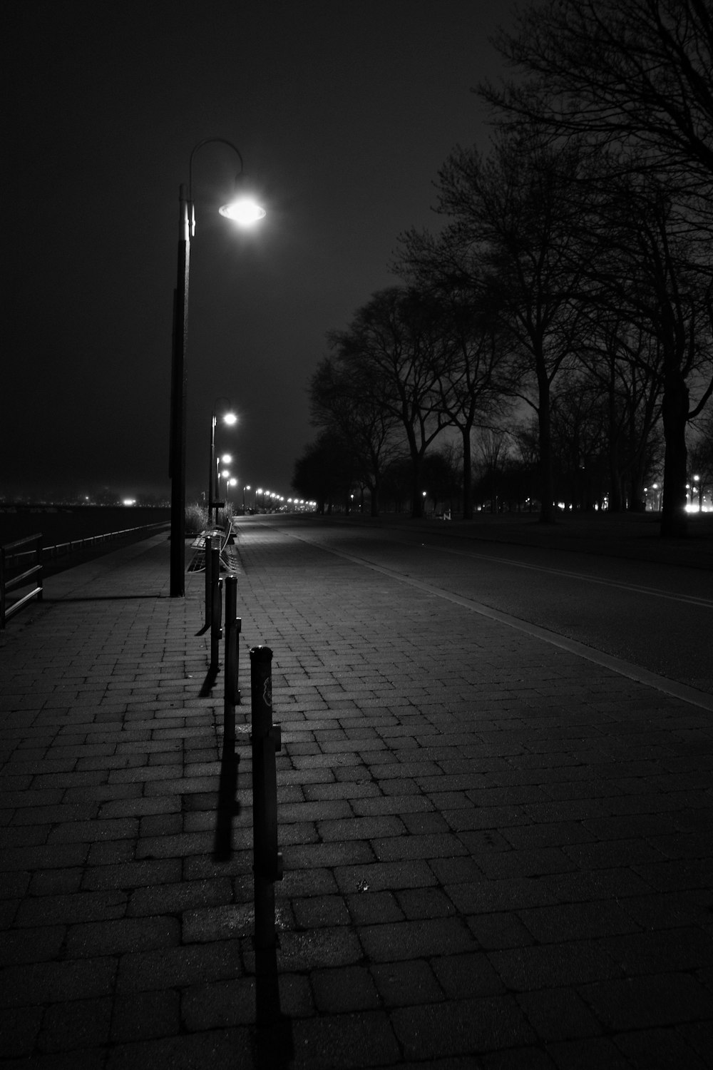 a black and white photo of a street at night