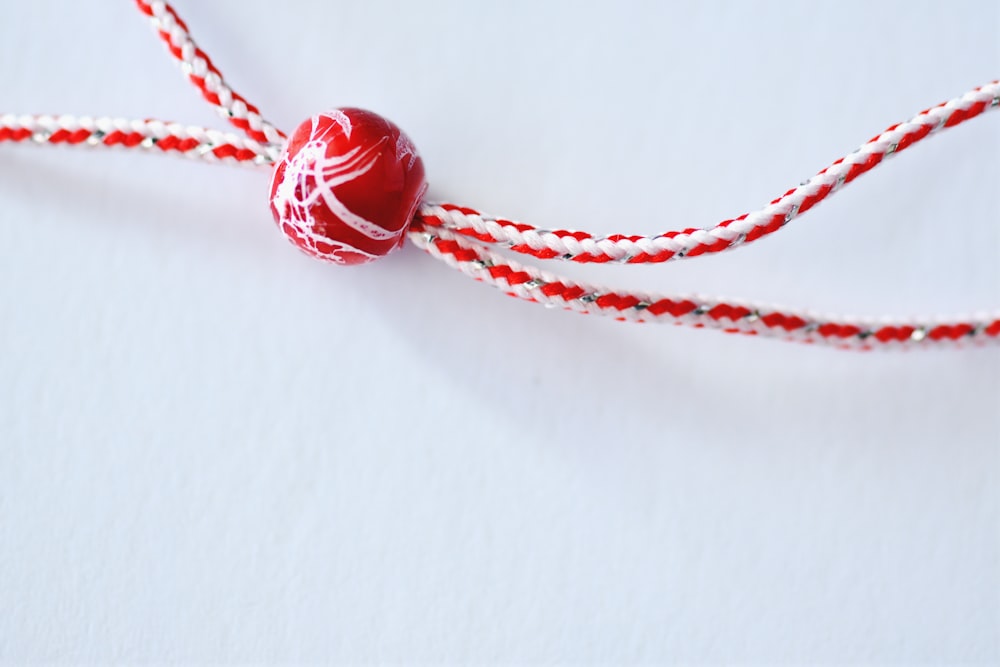 a red and white string with a red and white ball on it