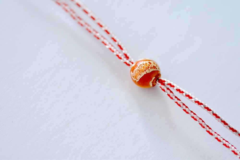 a red and white string with a bead on it