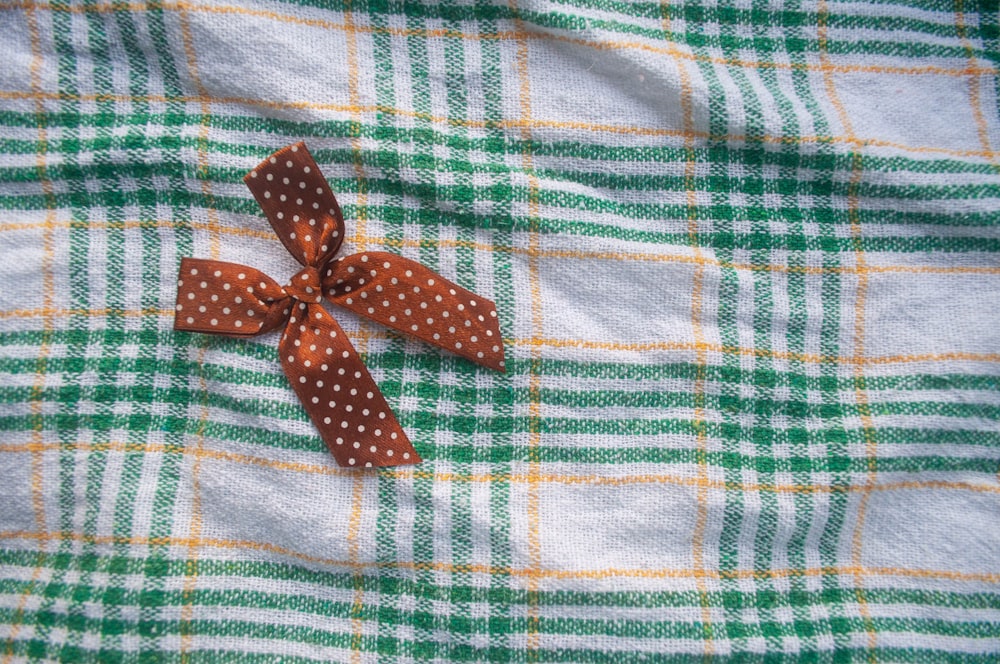 a brown polka dot bow on a green and white checkered fabric