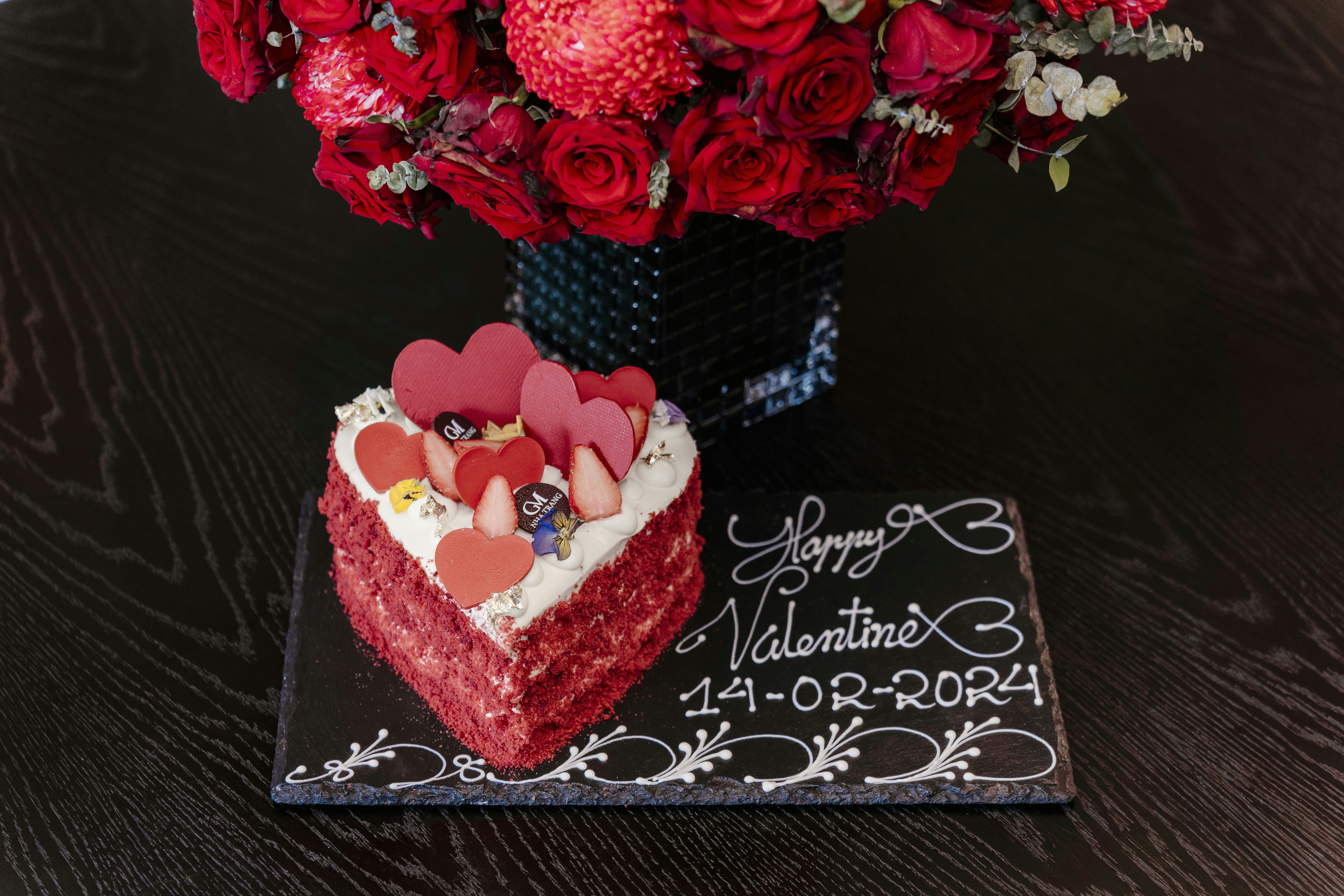 Heart-shaped red velvet cake with cream cheese frosting and rose petals for Valentines Day