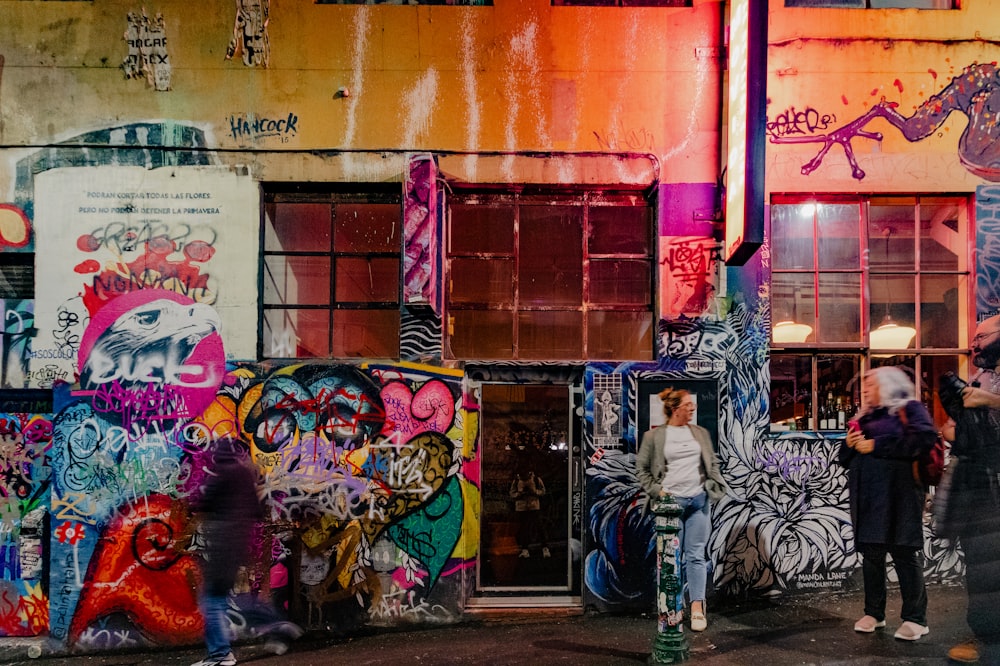 a group of people standing in front of a building covered in graffiti