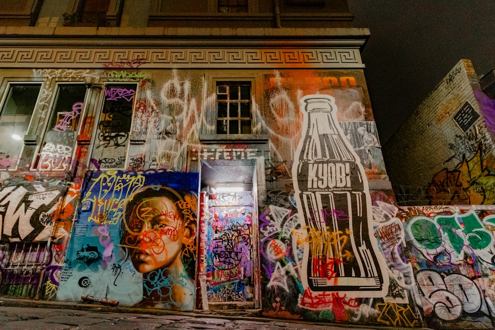 a building covered in lots of graffiti next to a tall building