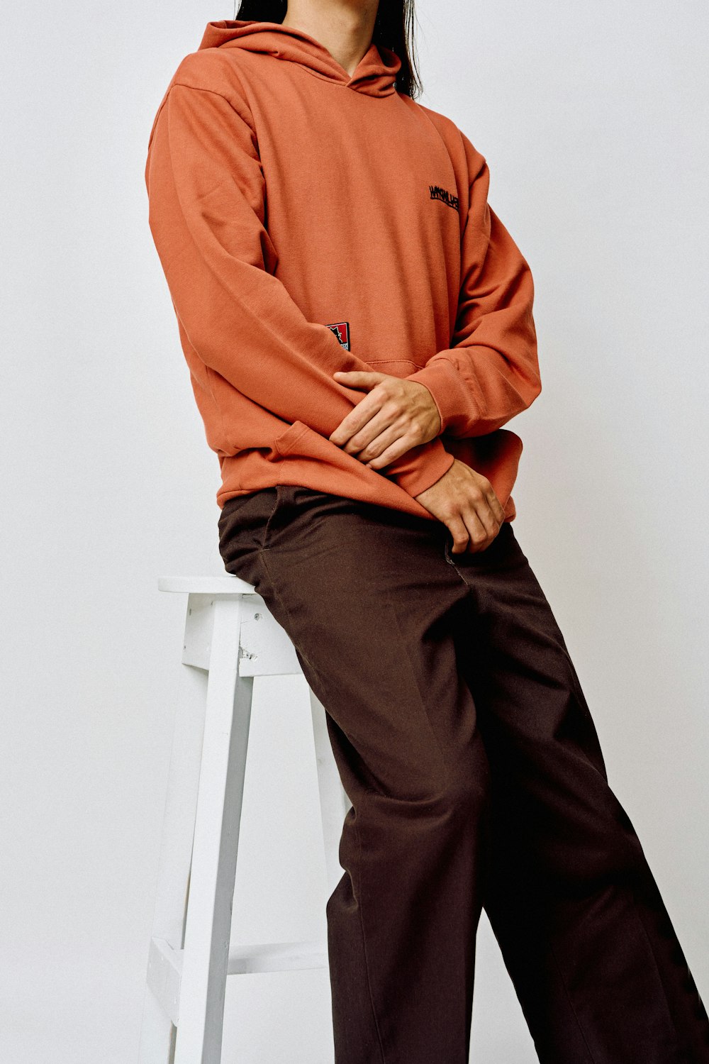 a woman sitting on a stool wearing a red hoodie