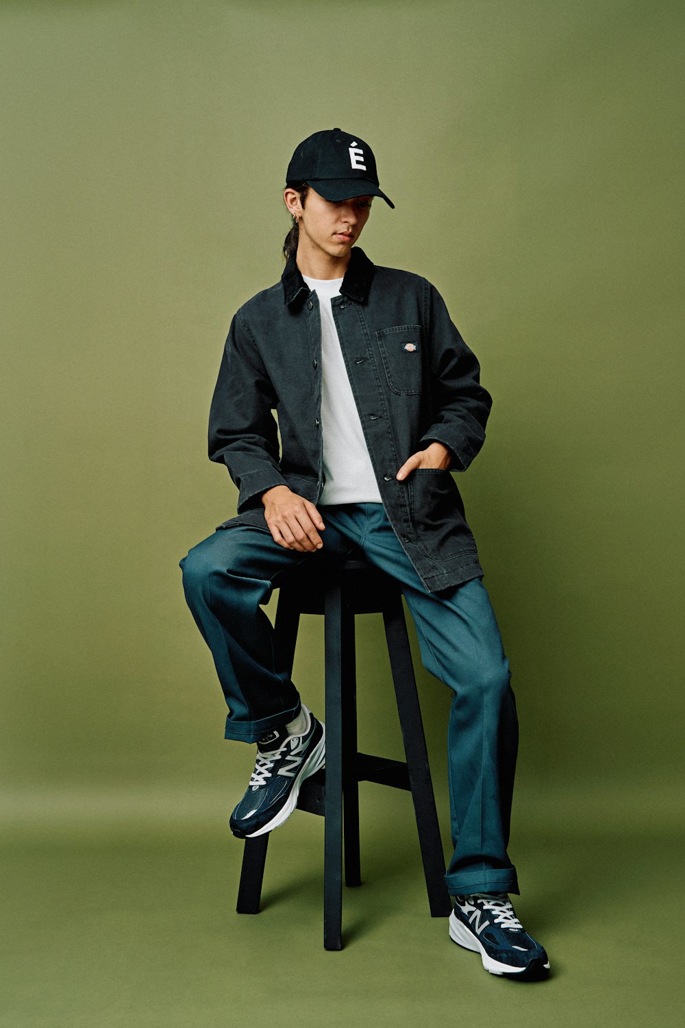 a man sitting on a stool wearing a hat
