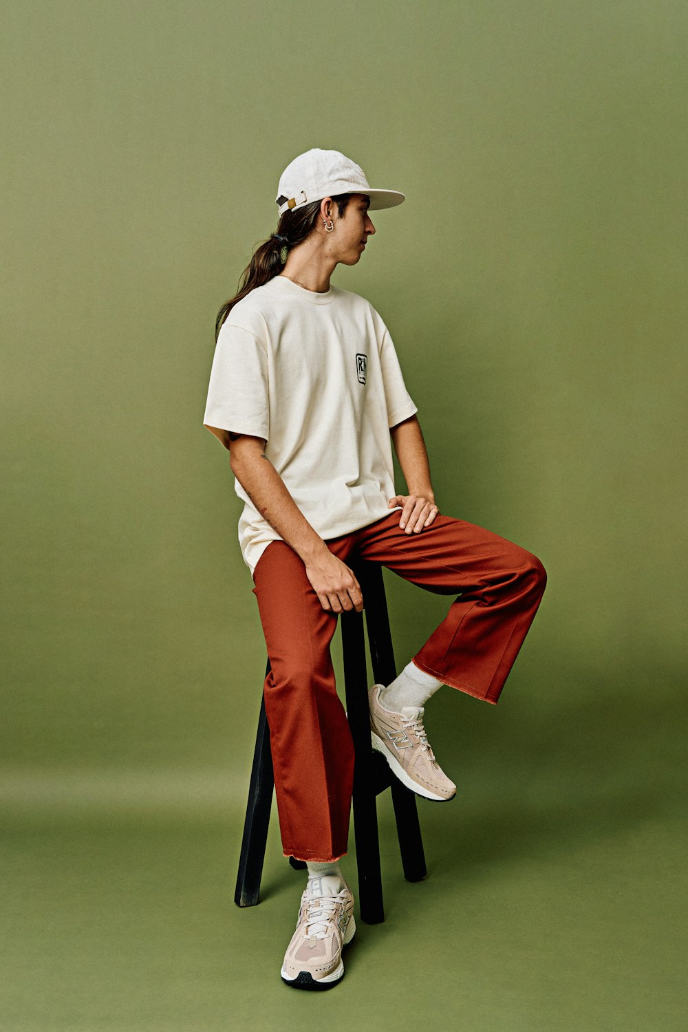 a woman sitting on a stool wearing a hat