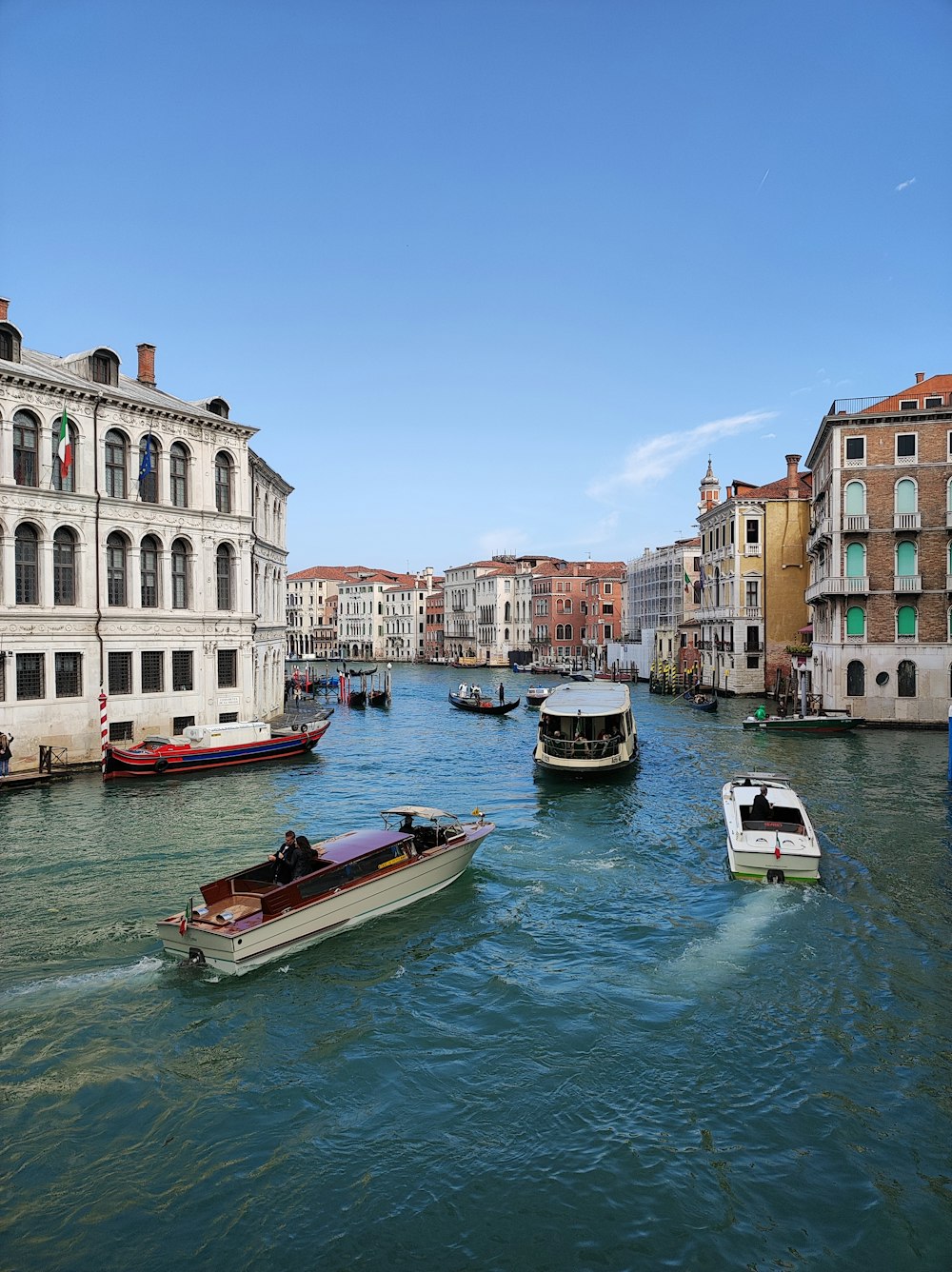 a group of boats floating down a river next to tall buildings