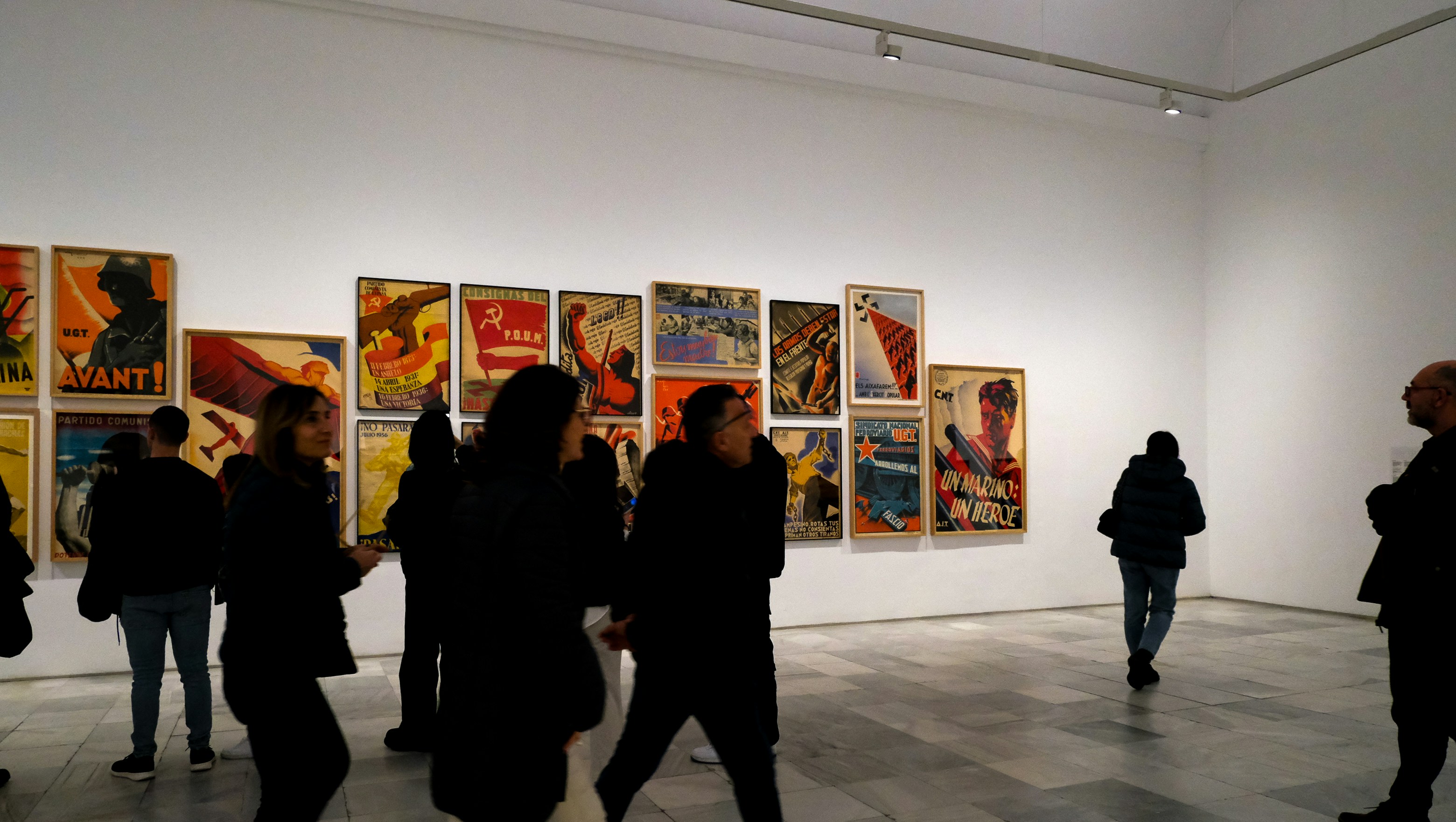 Bright gallery wall covered with colorful printed posters in an airy white room