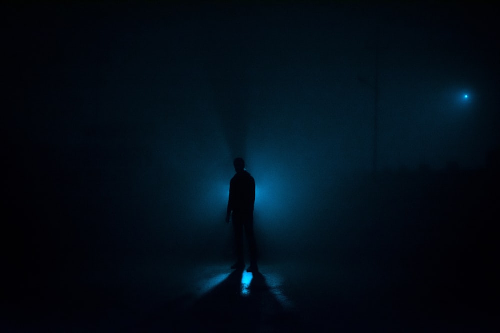 una persona parada en la oscuridad con una linterna