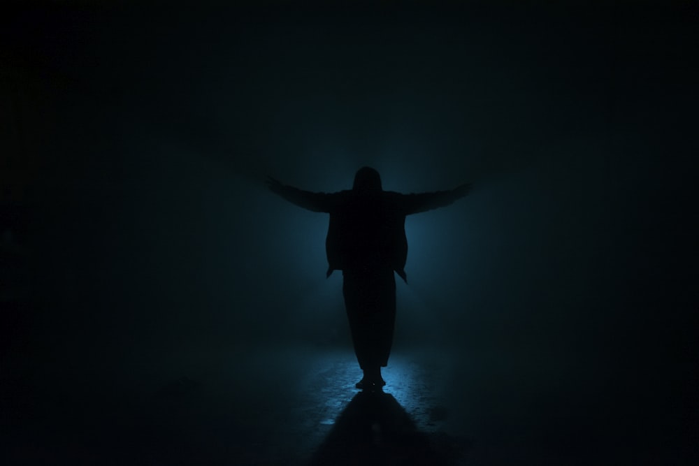 a person standing in the dark with their arms outstretched