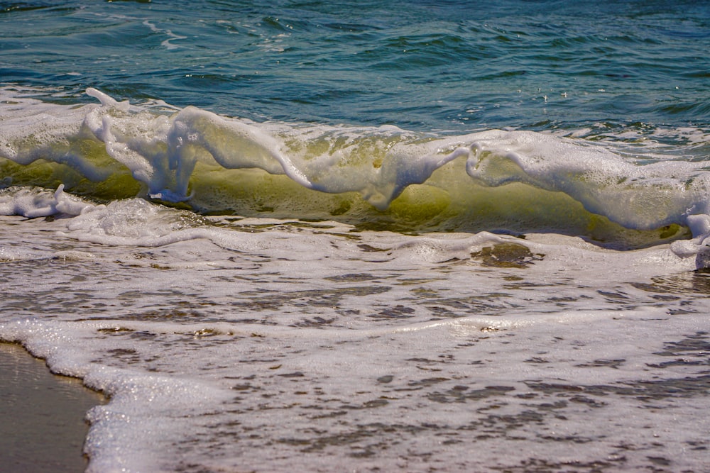 a wave rolls in on the beach with a surfboard in the background