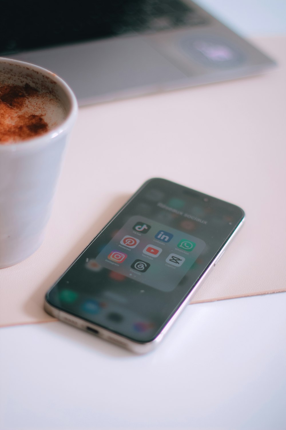 a cup of coffee next to a cell phone