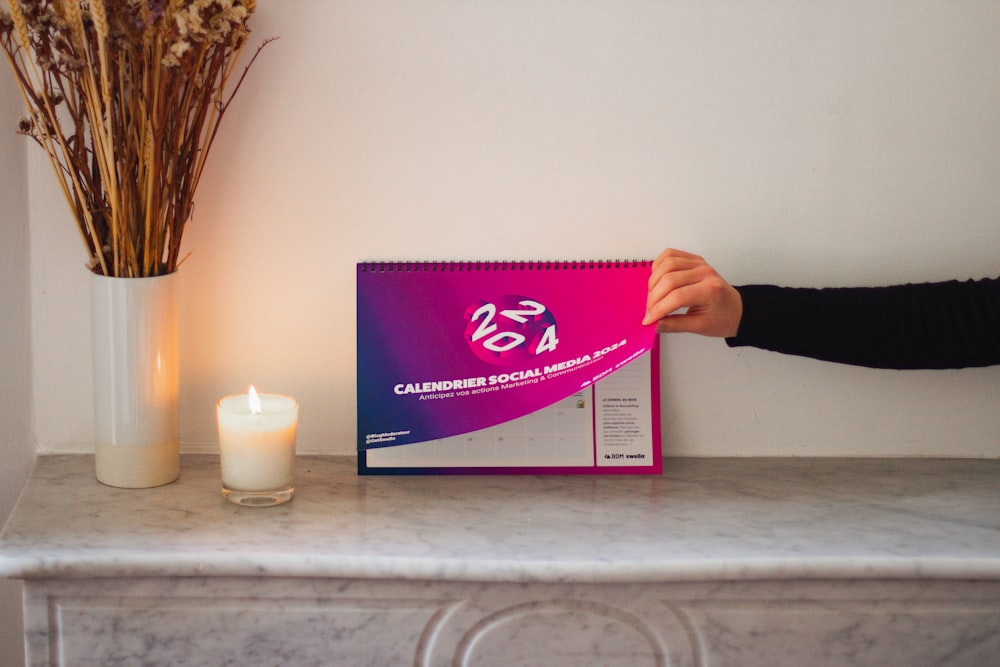 a person holding a calendar next to a candle