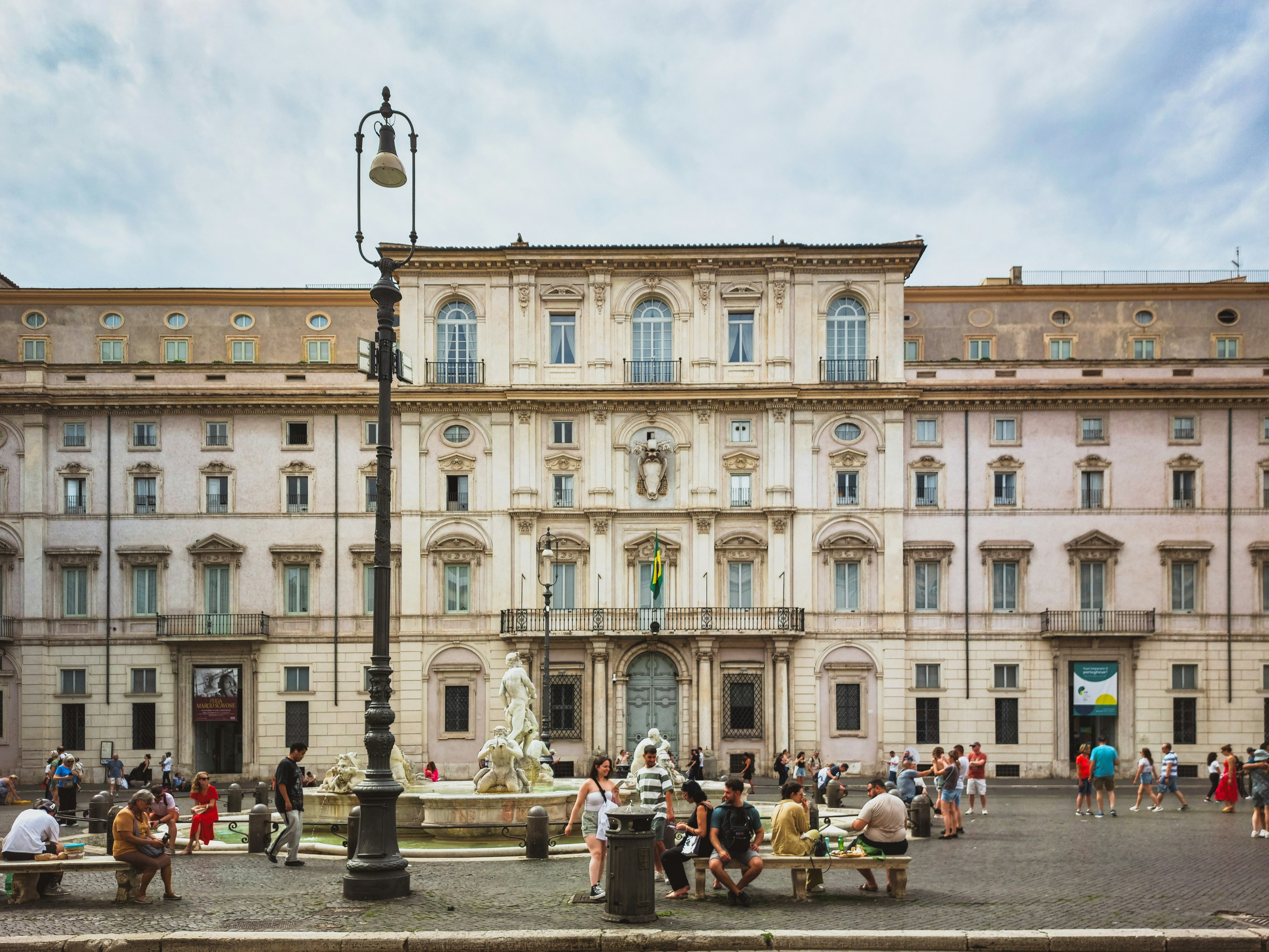 a group of people sitting around a fountain in front of a building