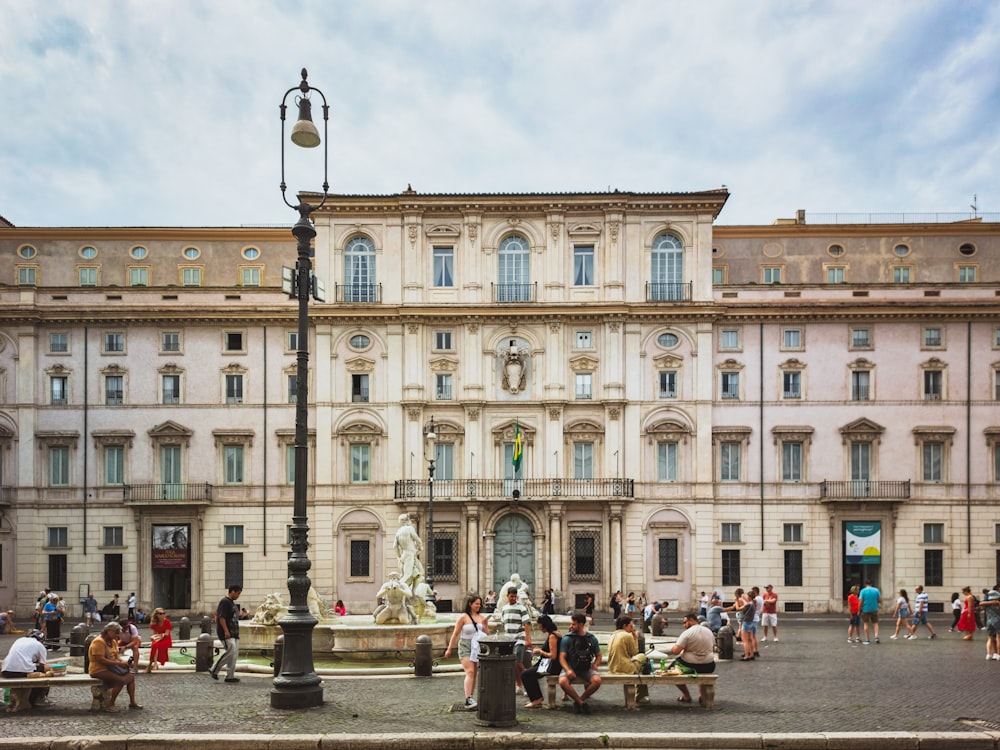 a group of people sitting around a fountain in front of a building