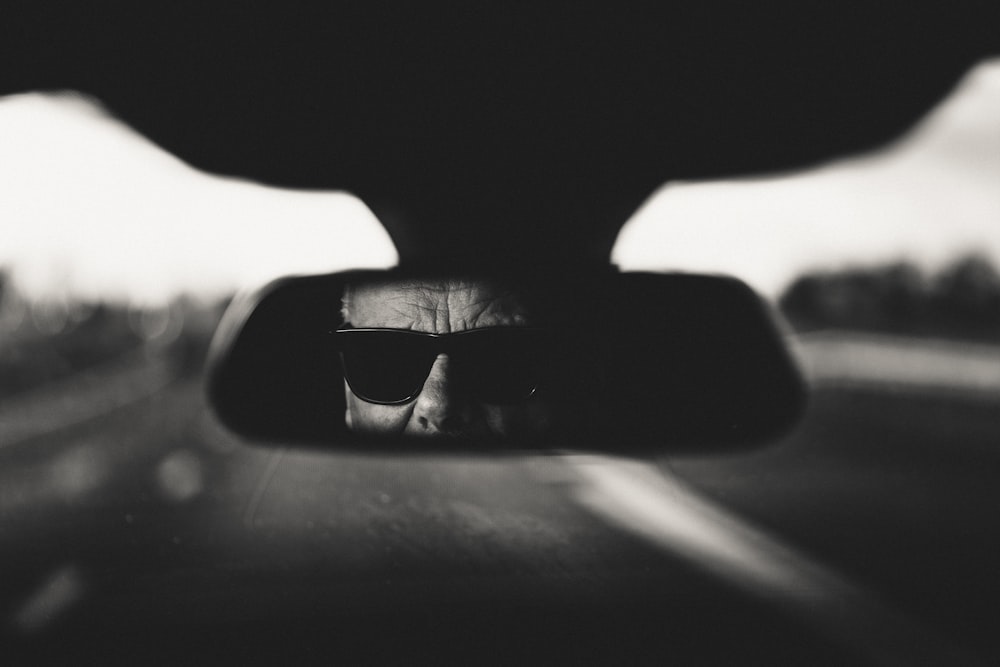 a rear view mirror reflecting a man in sunglasses