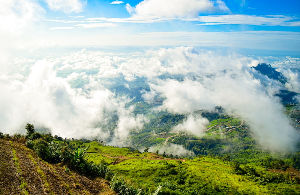 a lush green hillside covered in lots of clouds