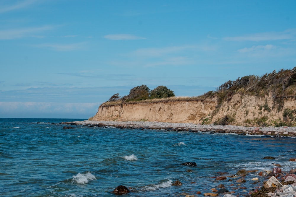 a body of water next to a rocky cliff