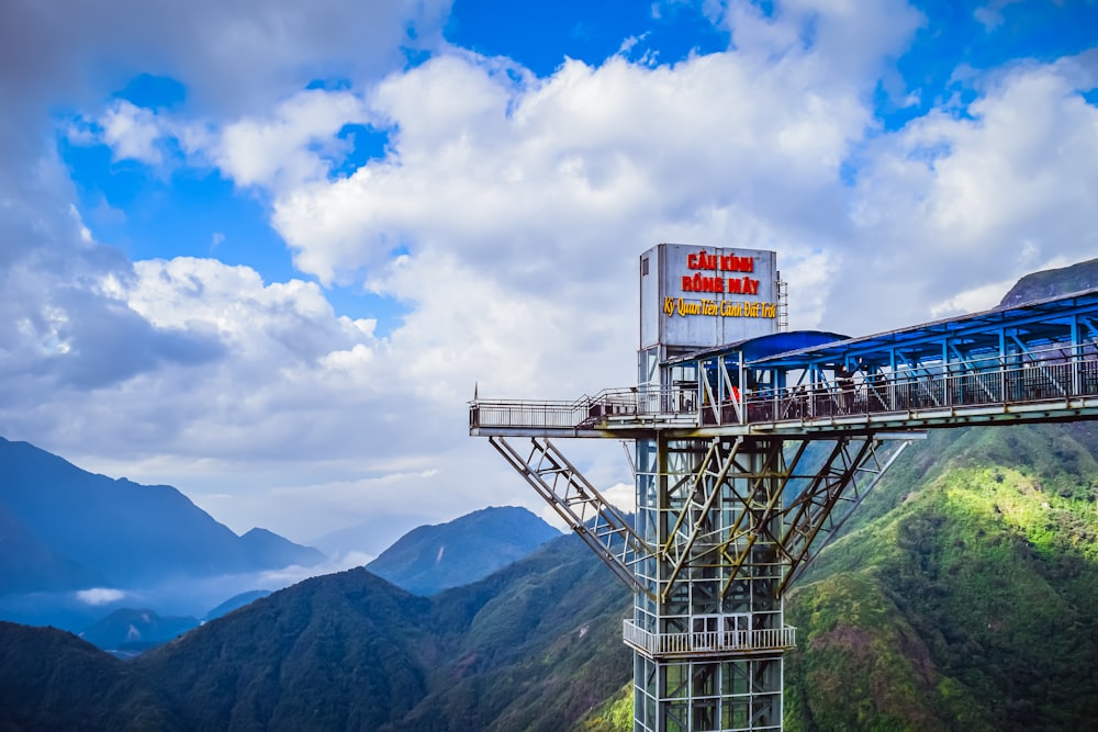 un tren azul que viaja sobre un puente en la cima de una montaña