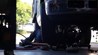 a man working on a vehicle under a truck