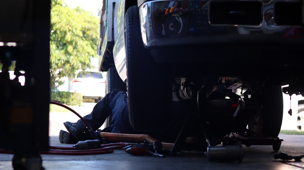 a man working on a vehicle under a truck