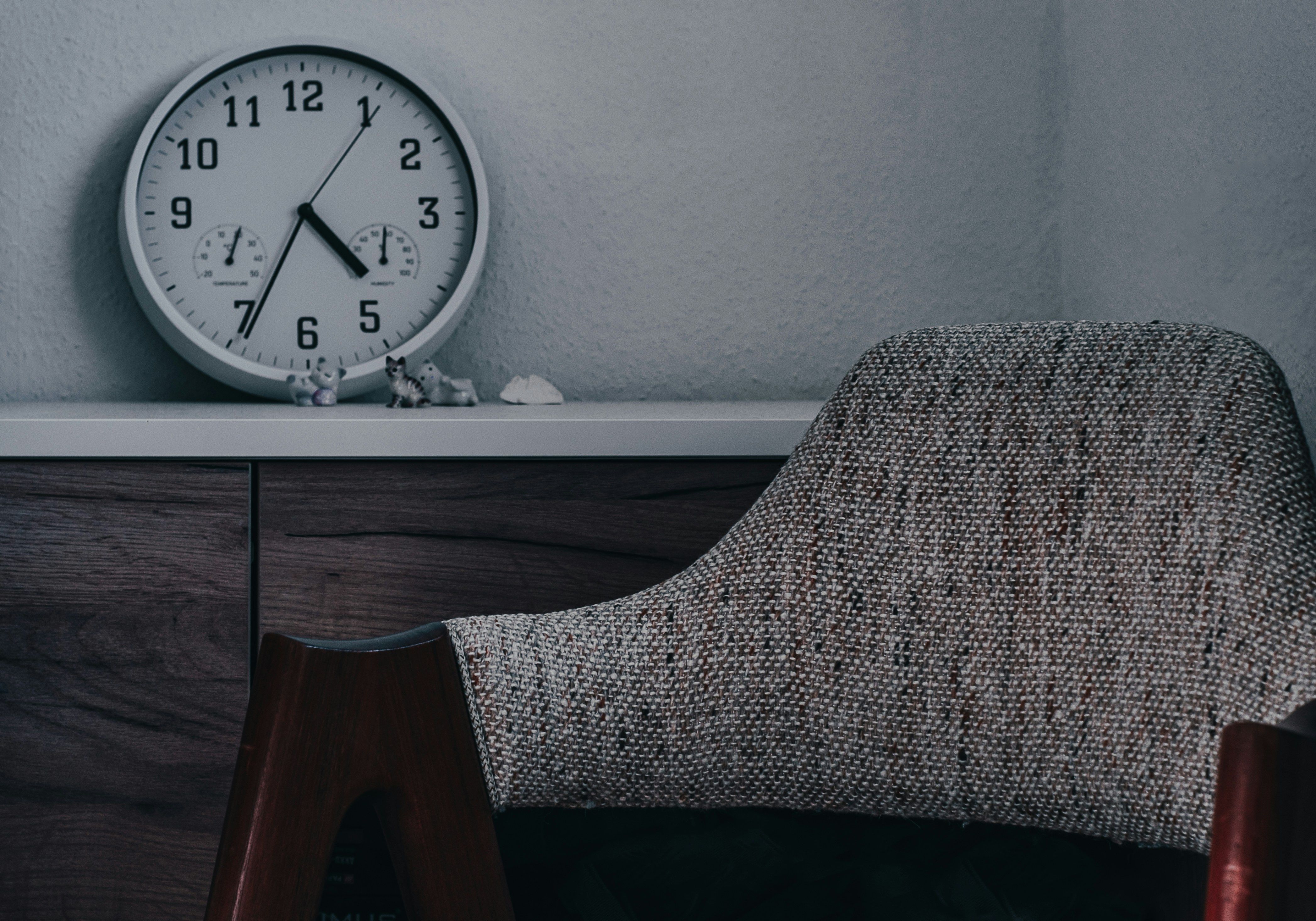 a clock sitting on top of a shelf next to a chair