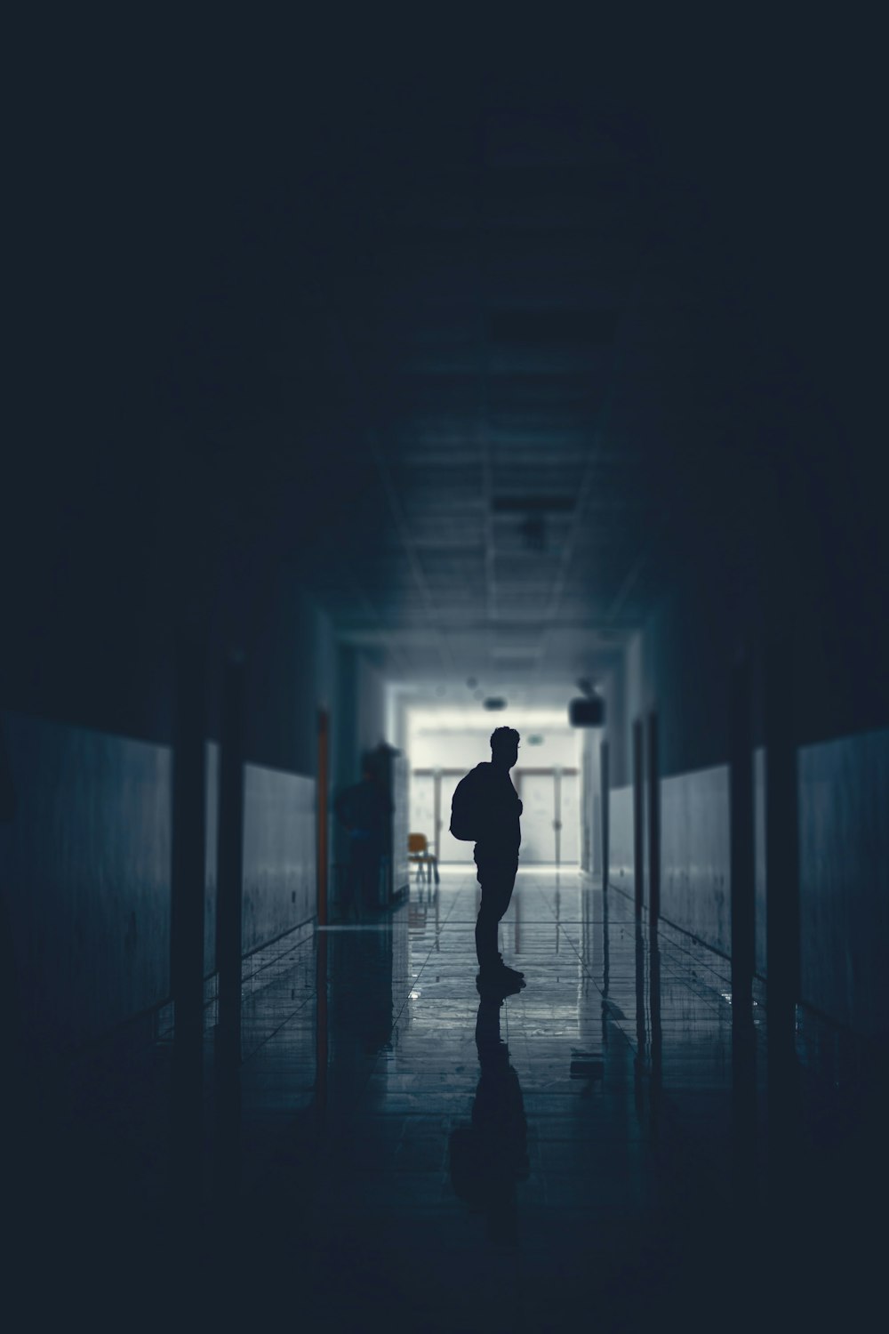 a person standing in a dark hallway with a backpack