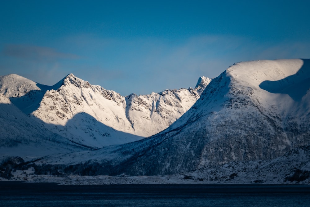 a mountain range covered in snow under a blue sky