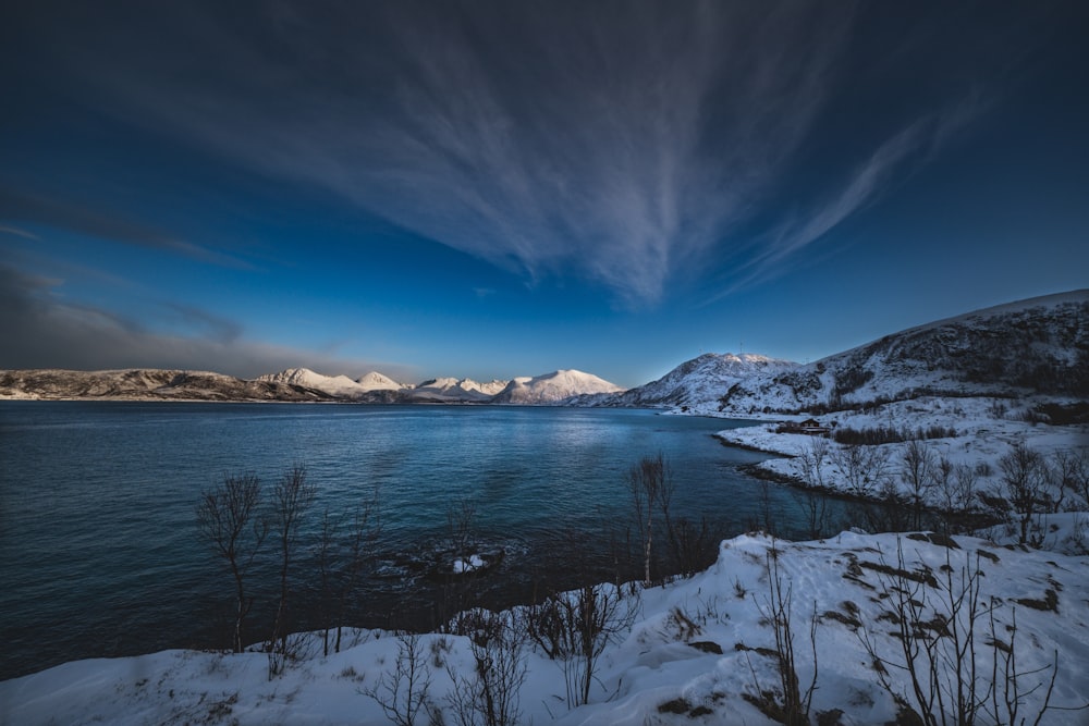 a body of water surrounded by snow covered mountains