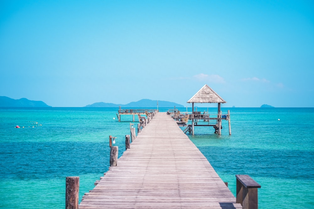 a wooden pier extending into the ocean with a hut on top of it