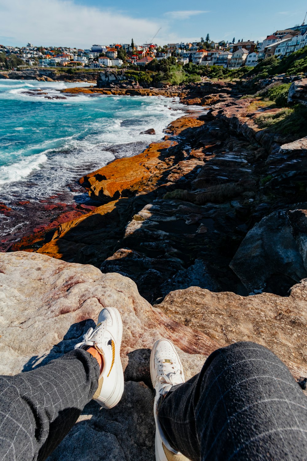 una persona seduta su una roccia vicino all'oceano