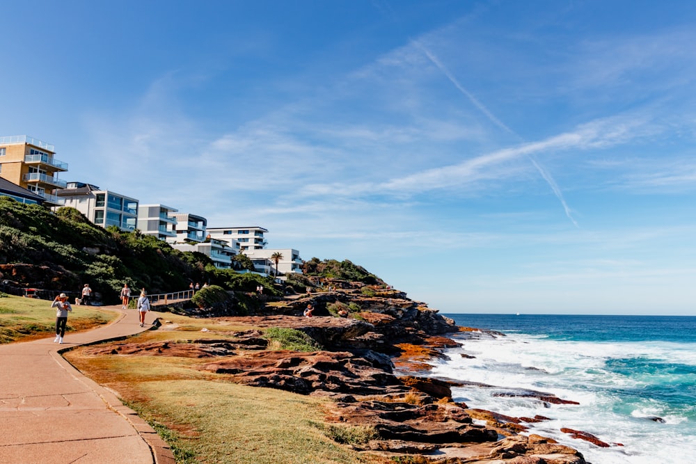 a couple of people walking down a path next to the ocean