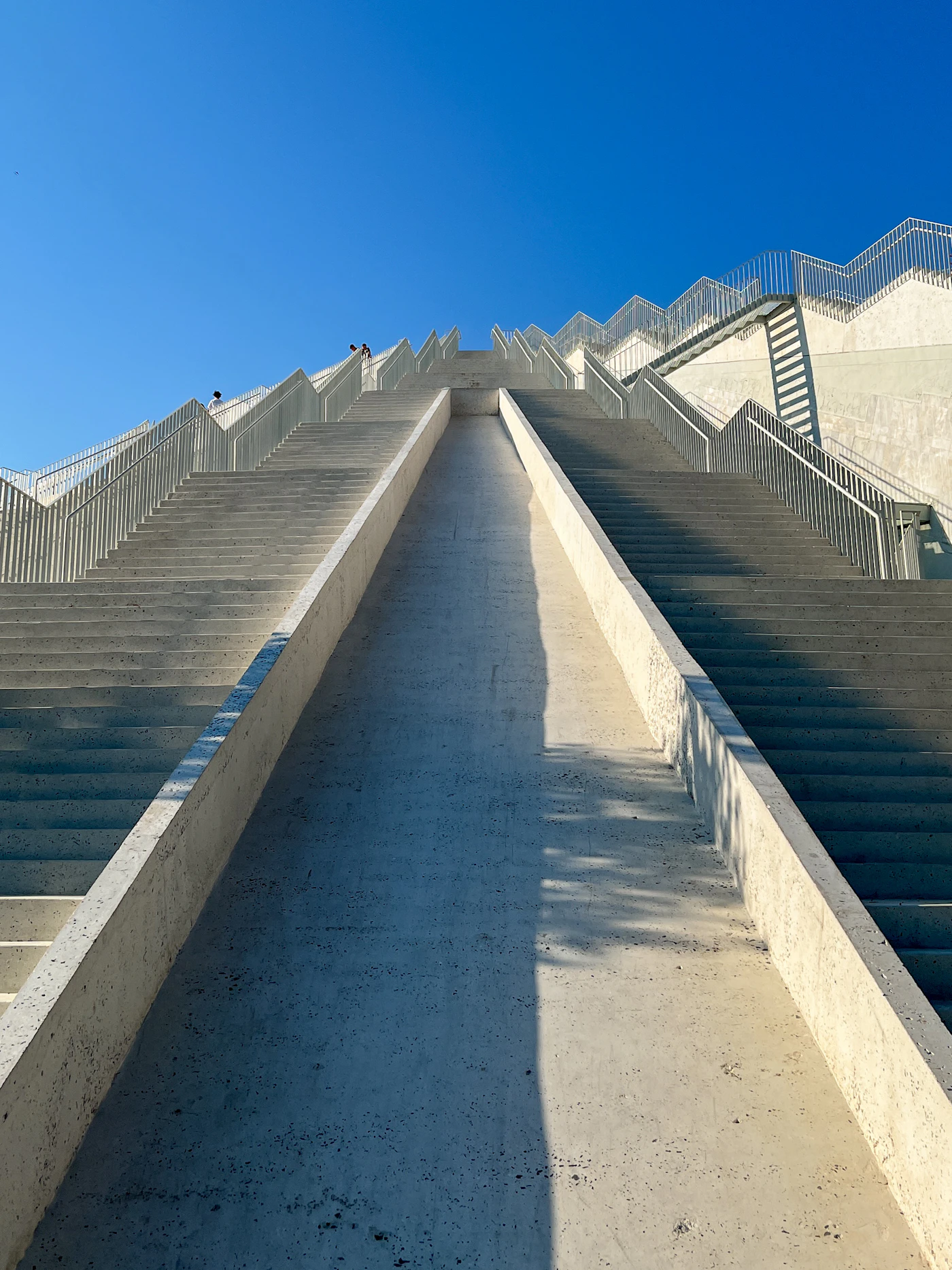 A concrete staircase rising between plain white walls