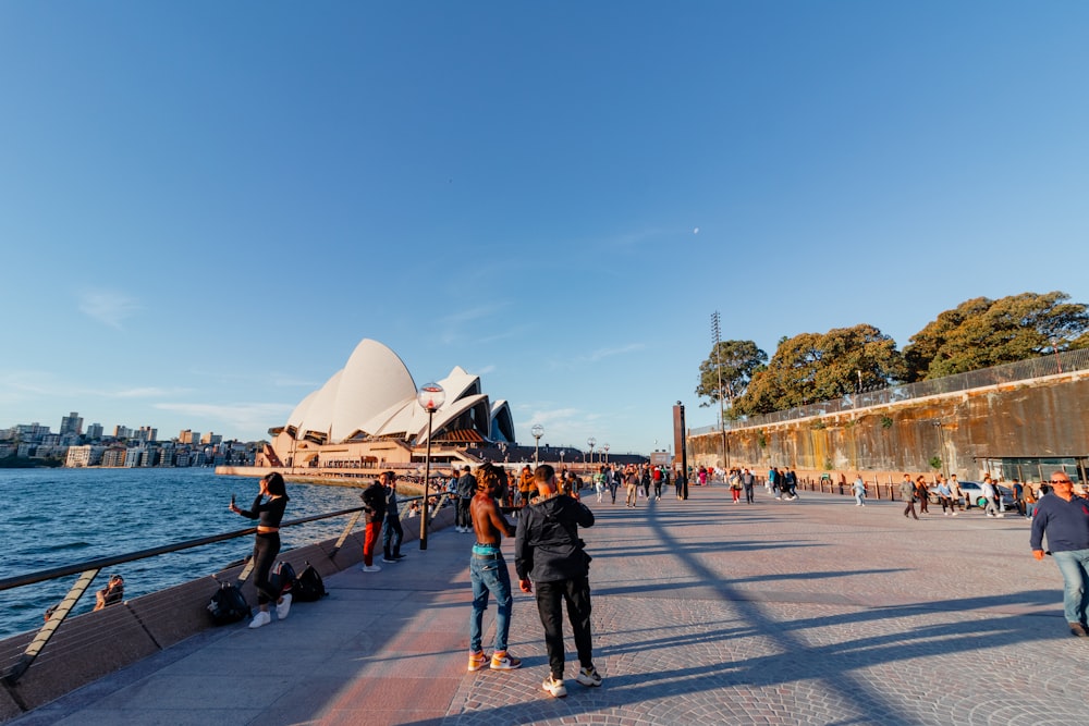 a group of people standing on a sidewalk next to a body of water