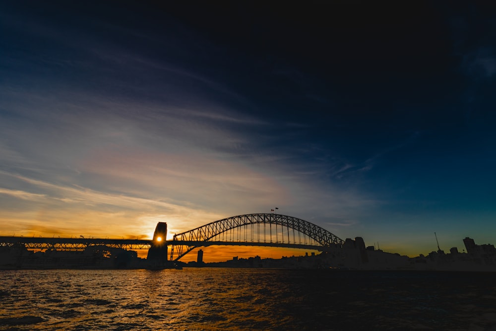 a bridge over water with a sunset in the background