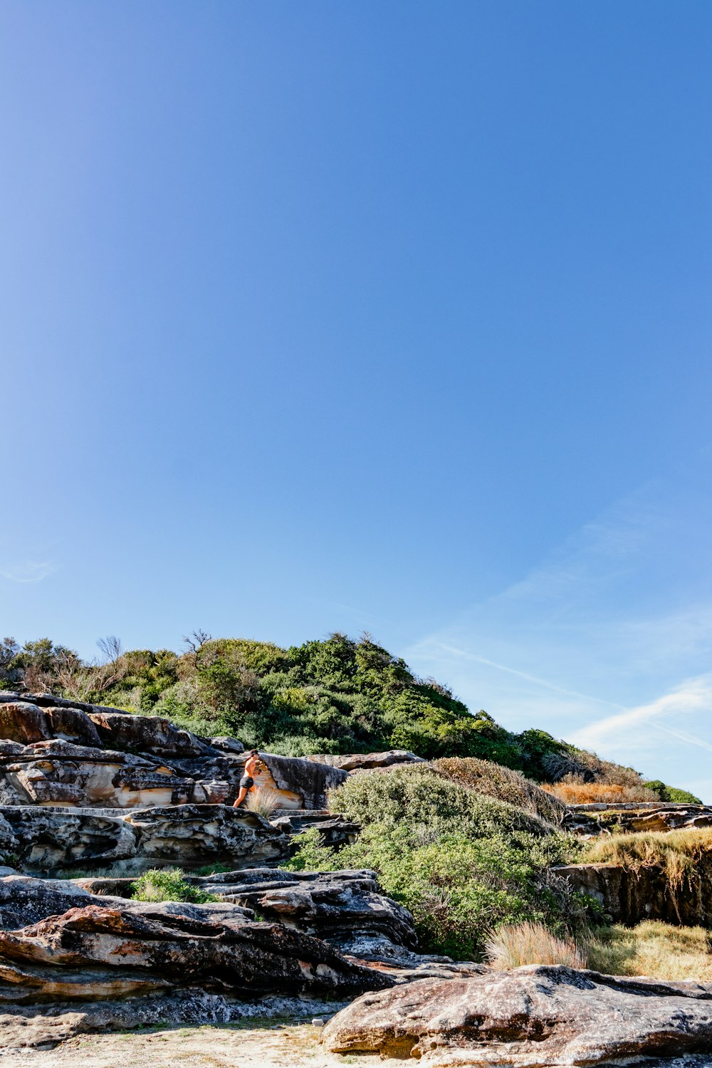 une personne debout au sommet d’une colline rocheuse