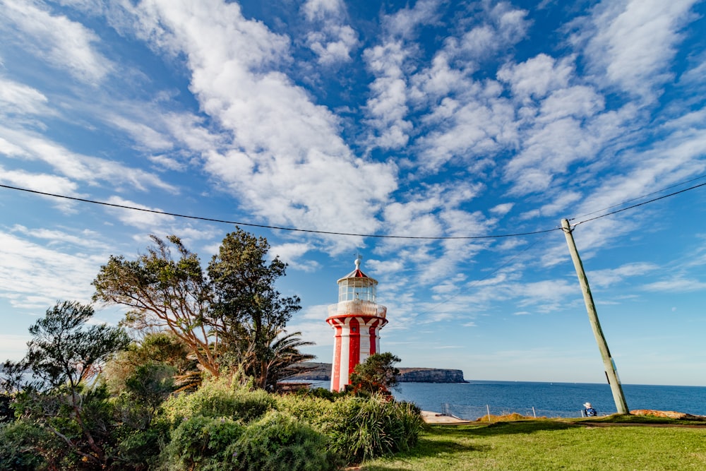 a red and white lighthouse sitting on top of a lush green field