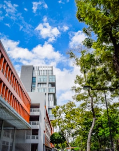 a tall building sitting next to a lush green forest