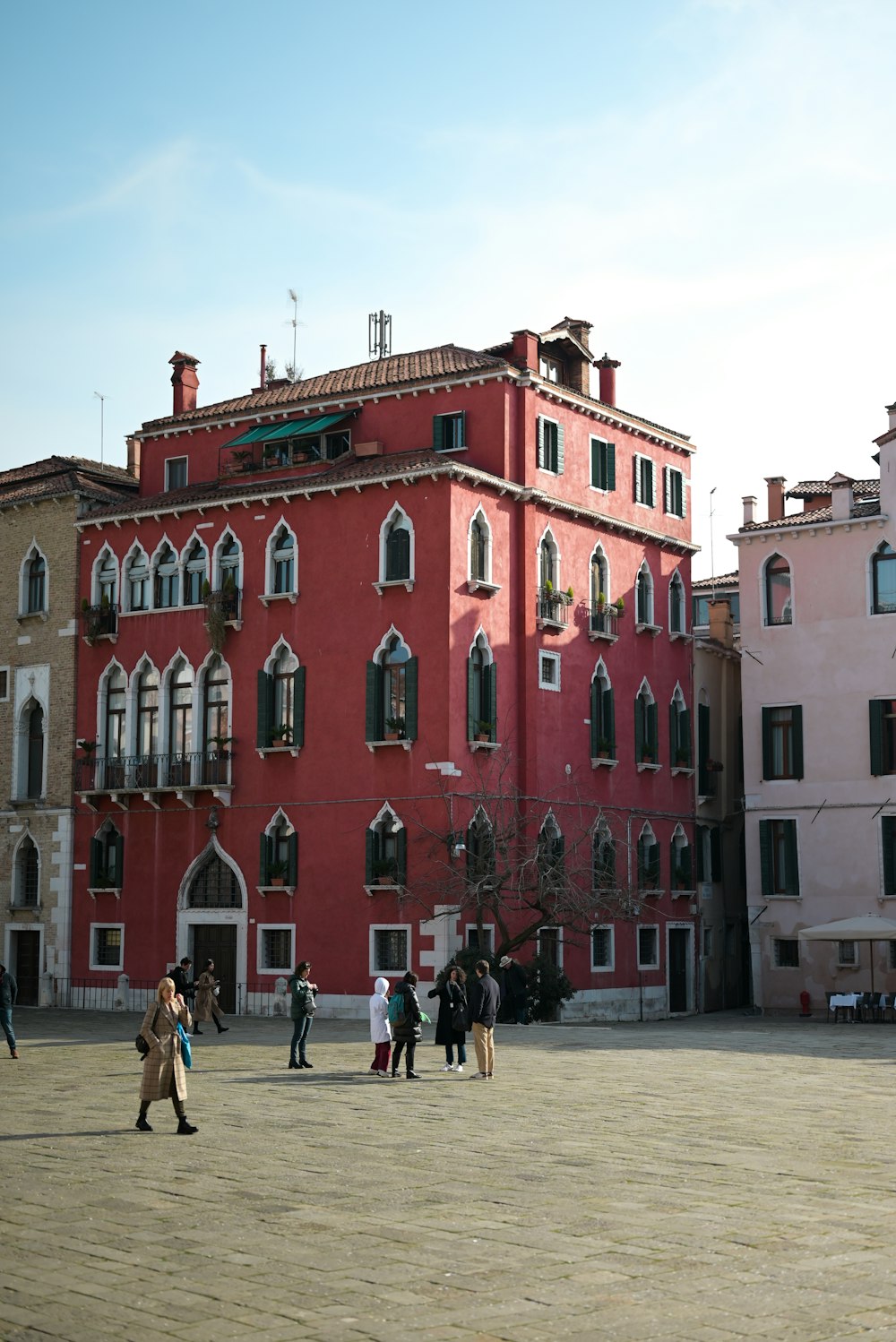 a group of people walking in front of a red building