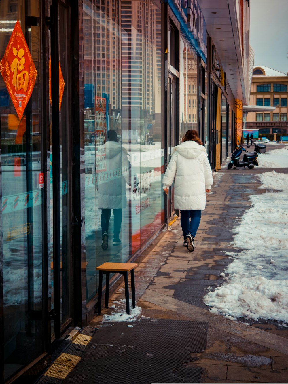 a woman walking down a sidewalk in front of a store