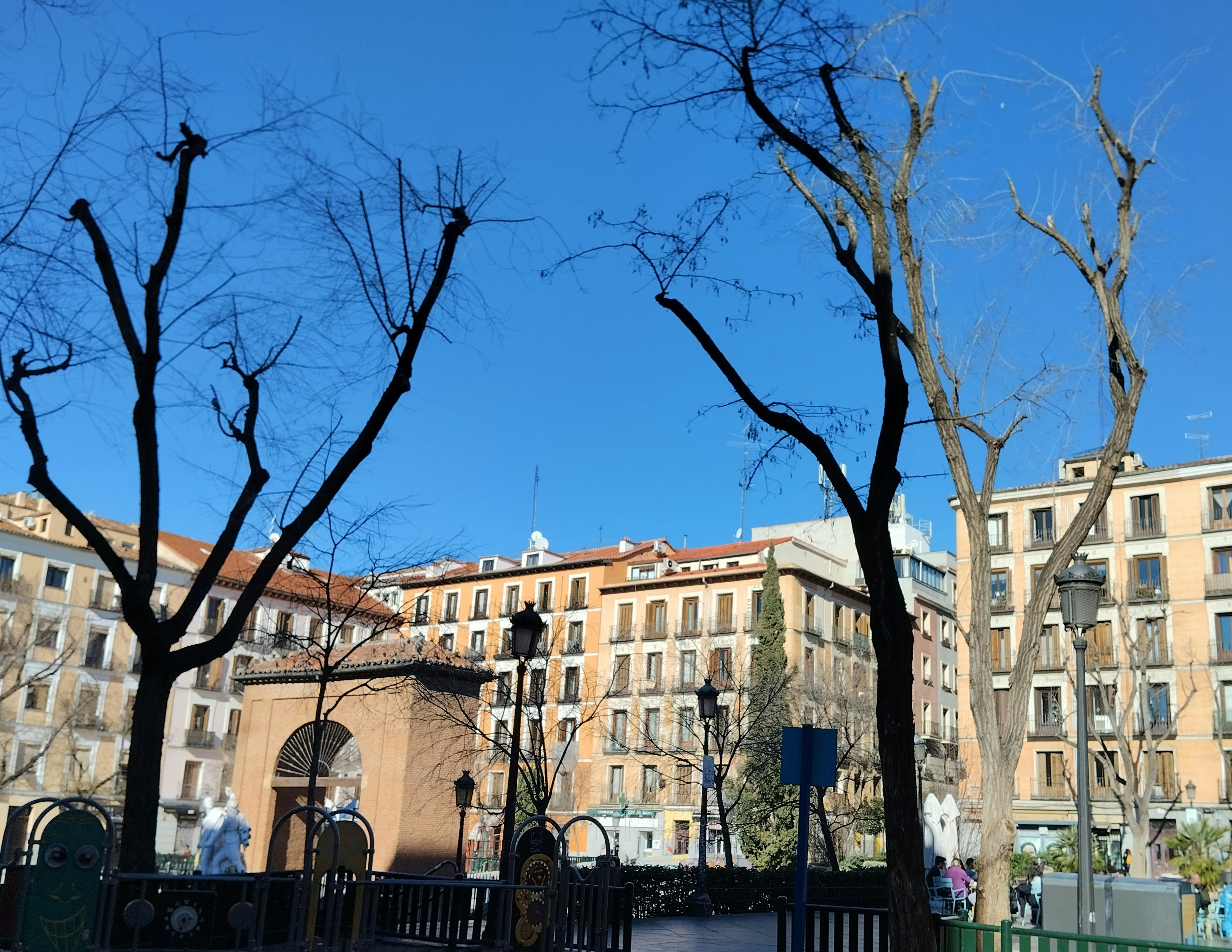 a park with benches and trees in front of a building