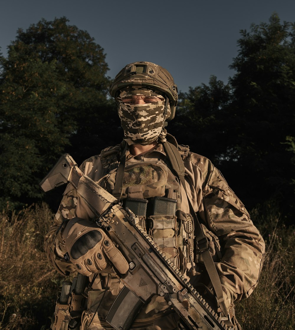 a man in camouflage holding a rifle in a field