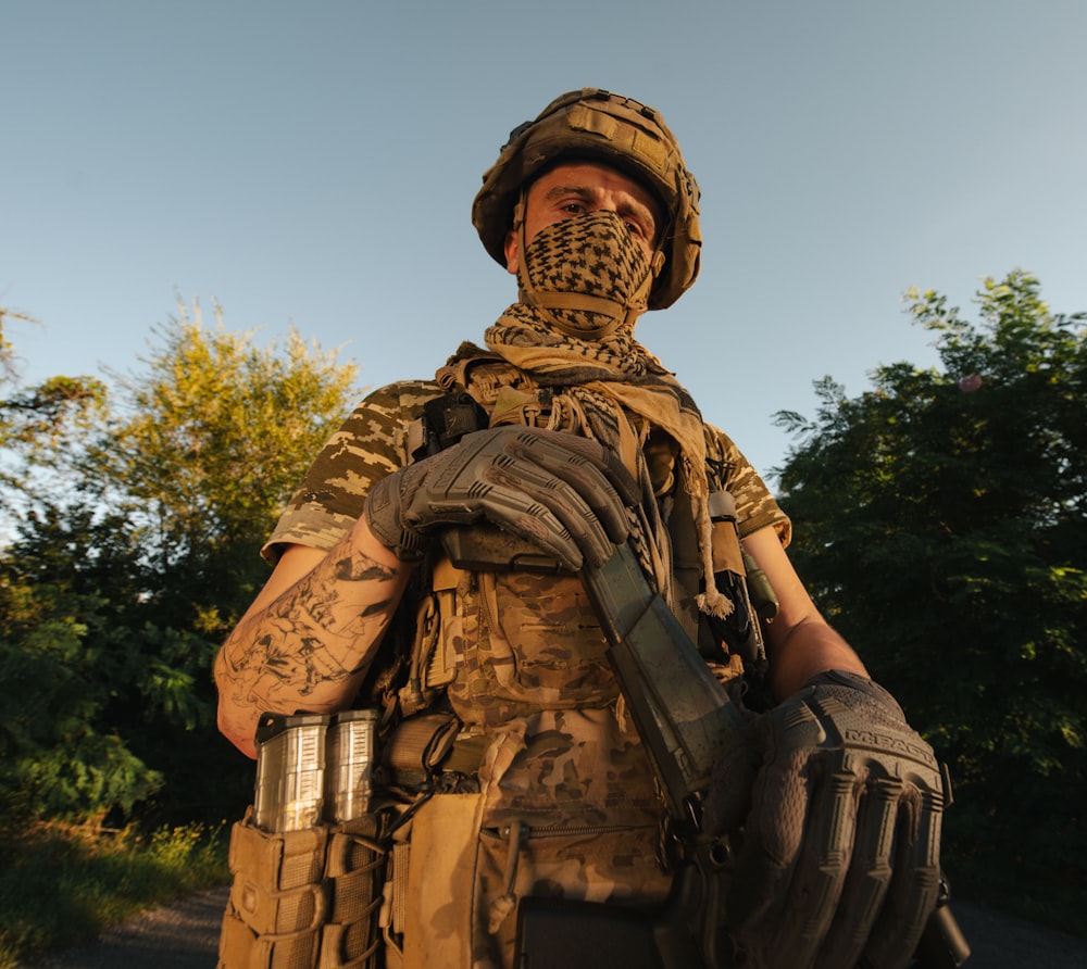 a man in camouflage holding a pair of gloves