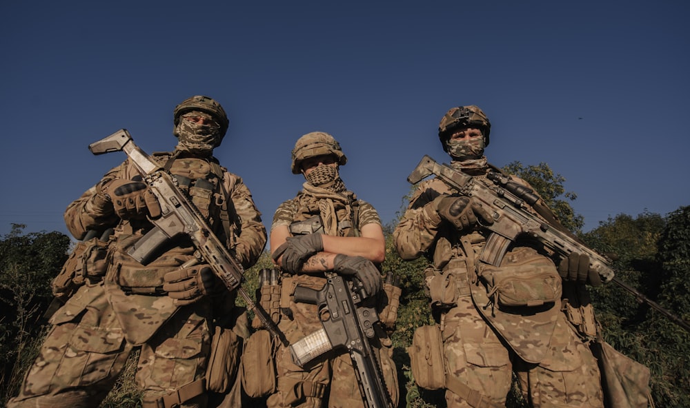 a group of men in camouflage holding guns