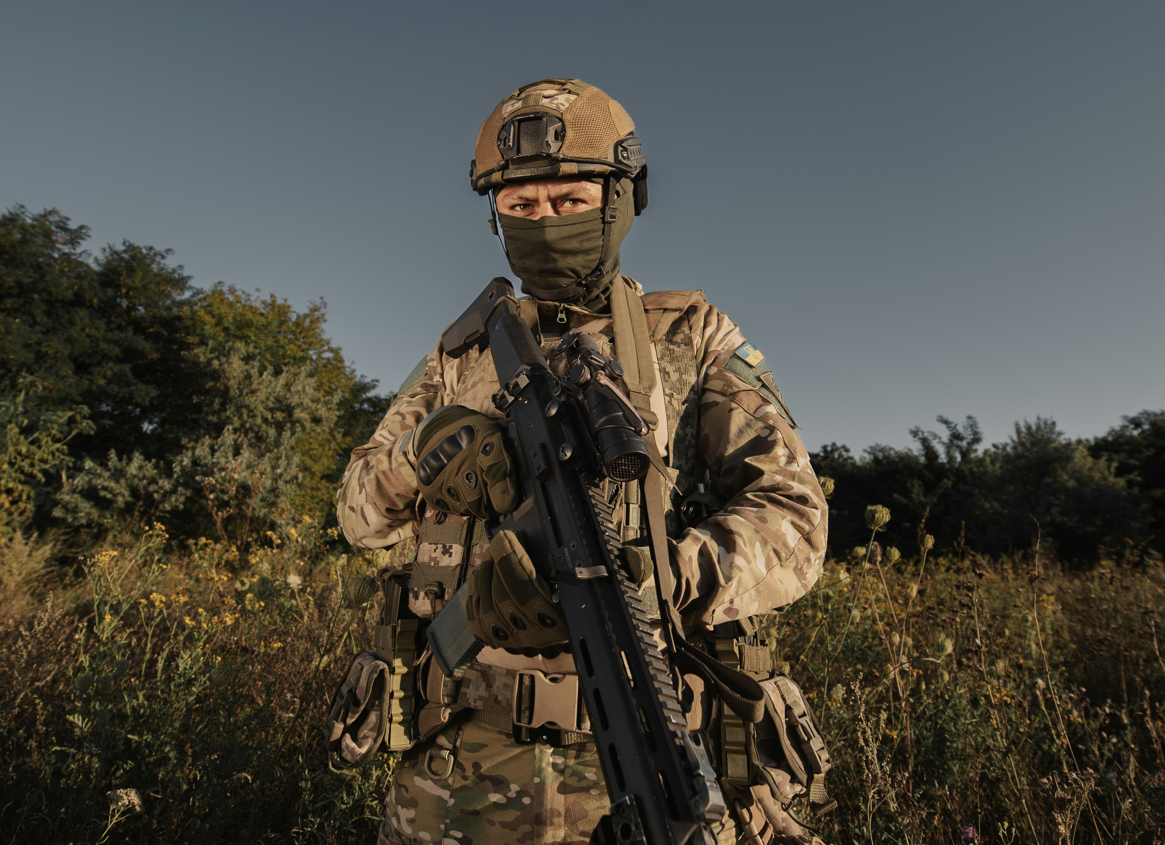 a man in camouflage holding a rifle in a field