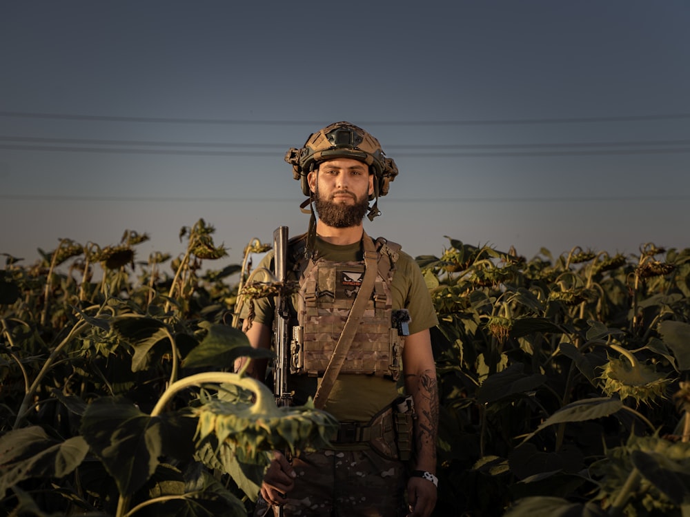 a man in a field of sunflowers holding a rifle