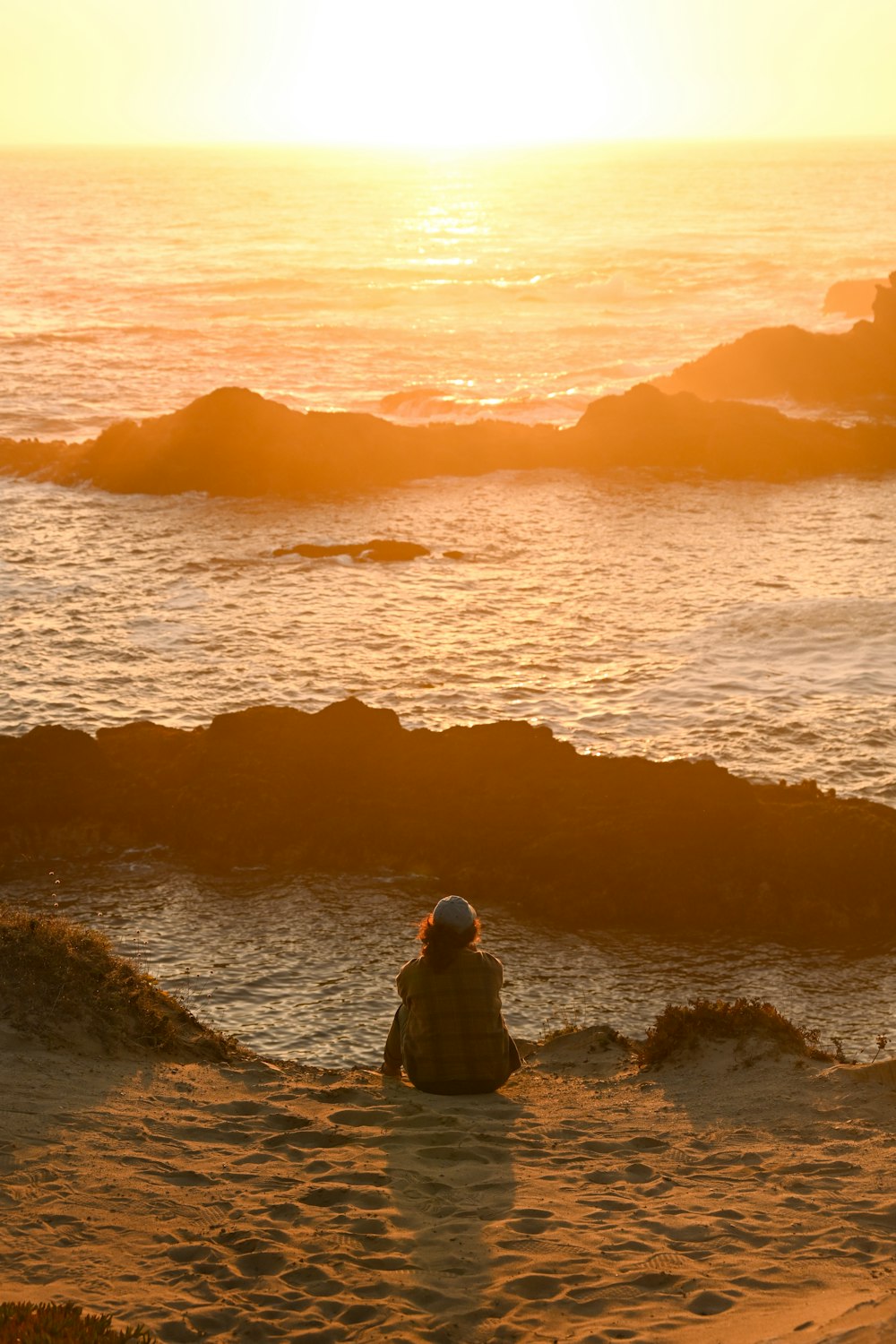 a person sitting in the sand near the ocean