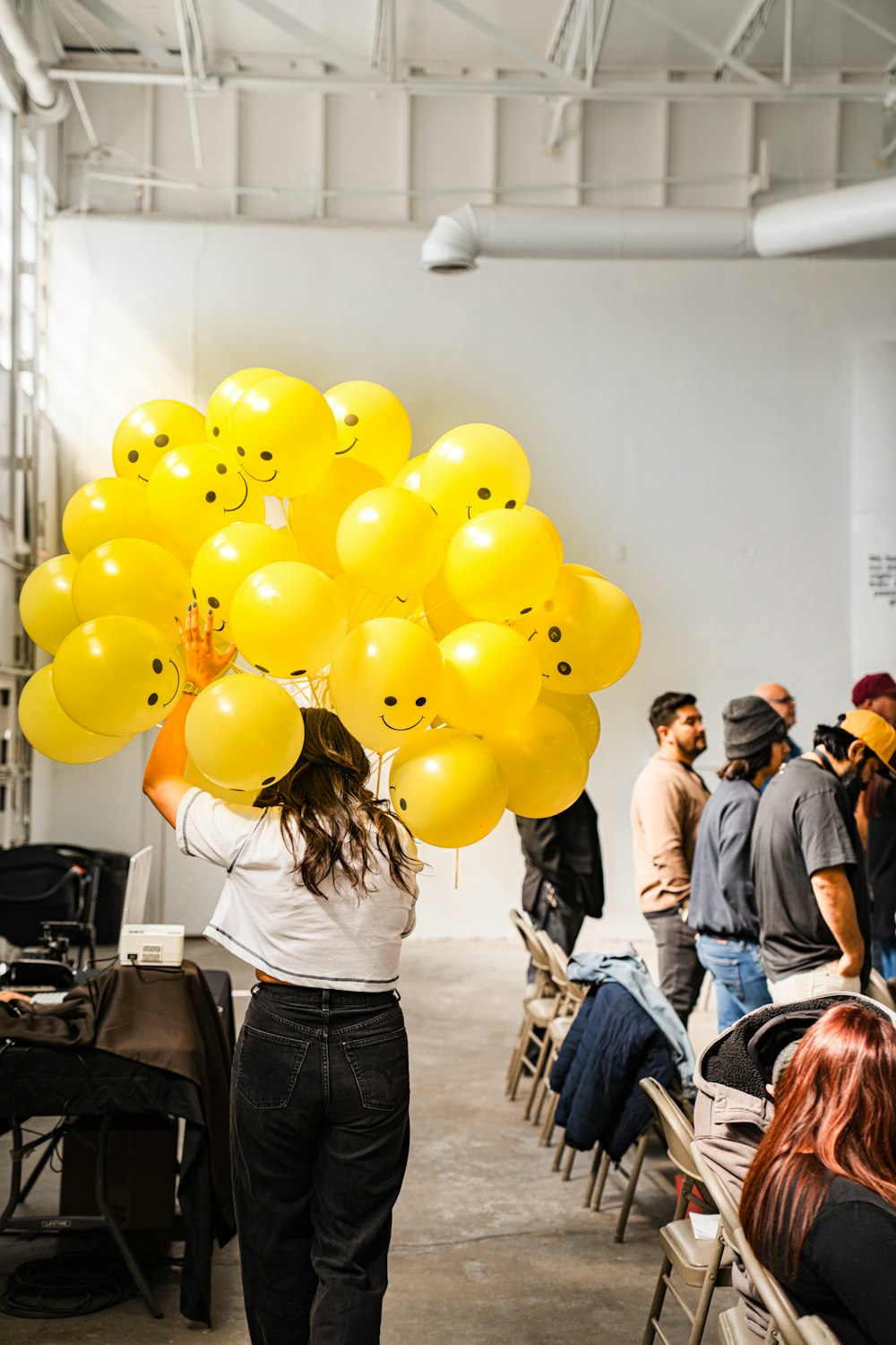a woman holding a bunch of yellow balloons