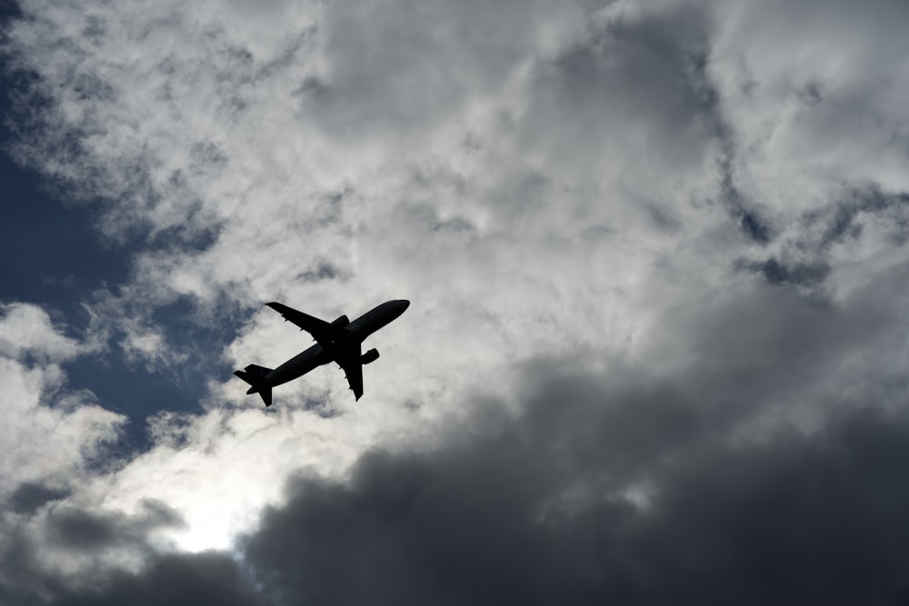 un avión volando a través de un cielo azul nublado